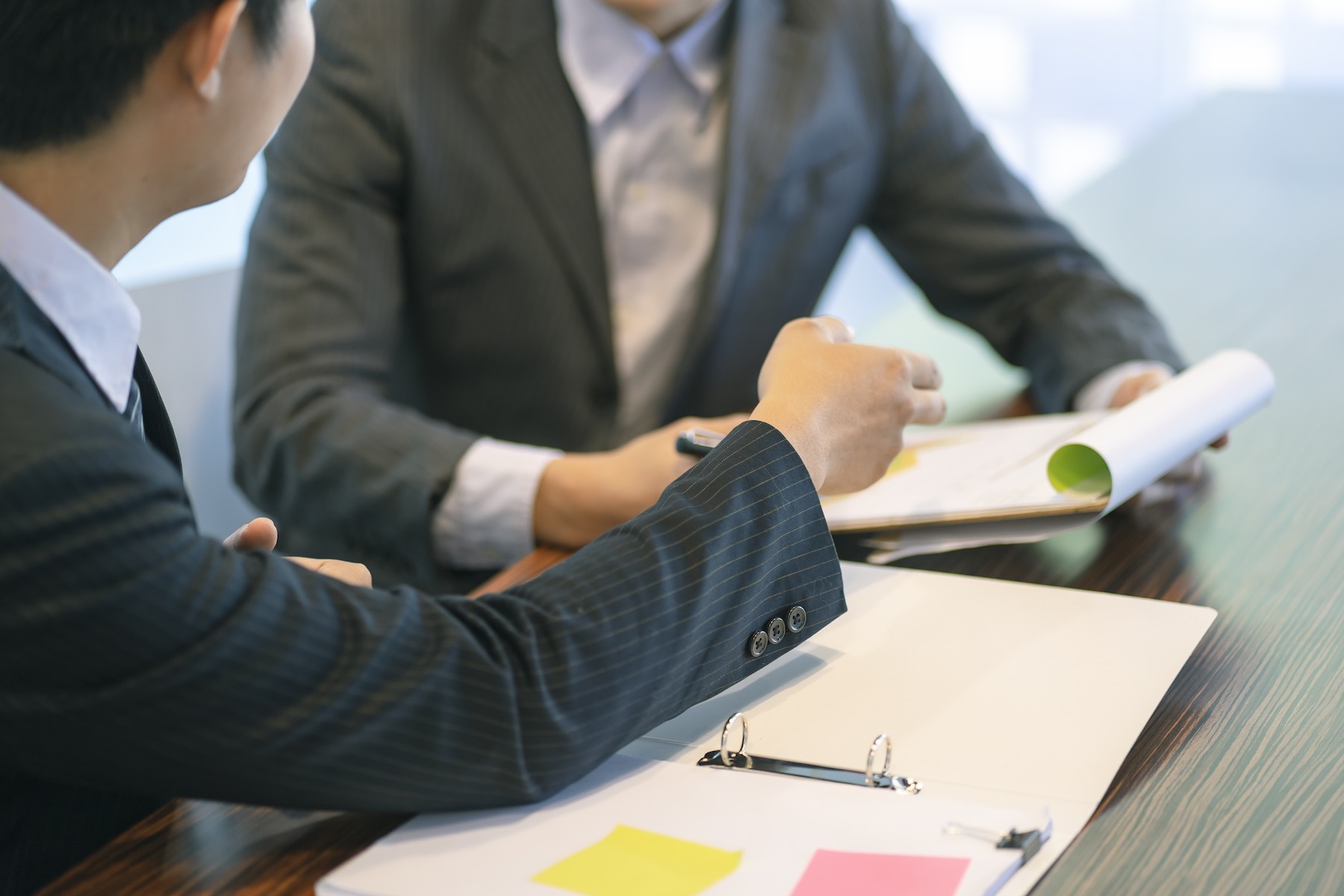 midsection-businessmen-discussing-paperwork-desk-office